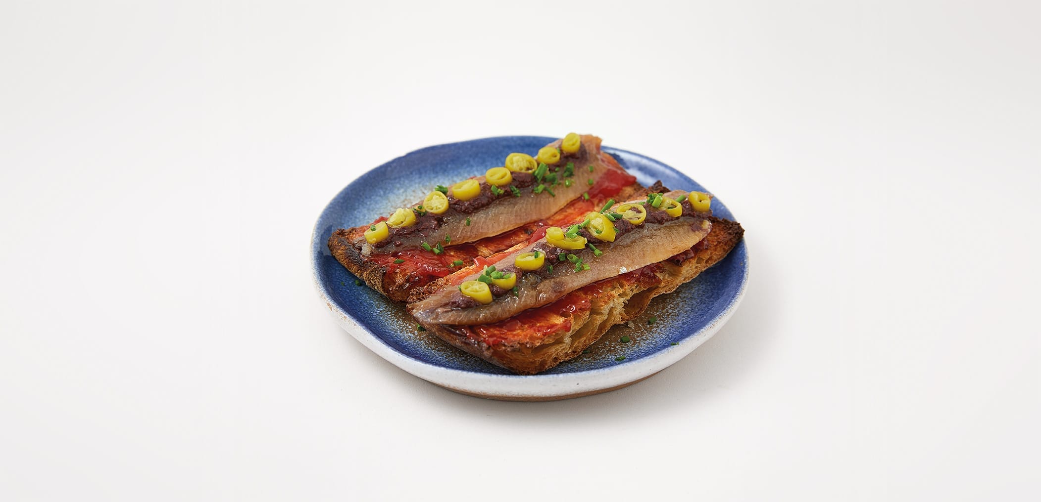 Tosta de sardina ahumada con mermelada de tomate, olivada y piparra