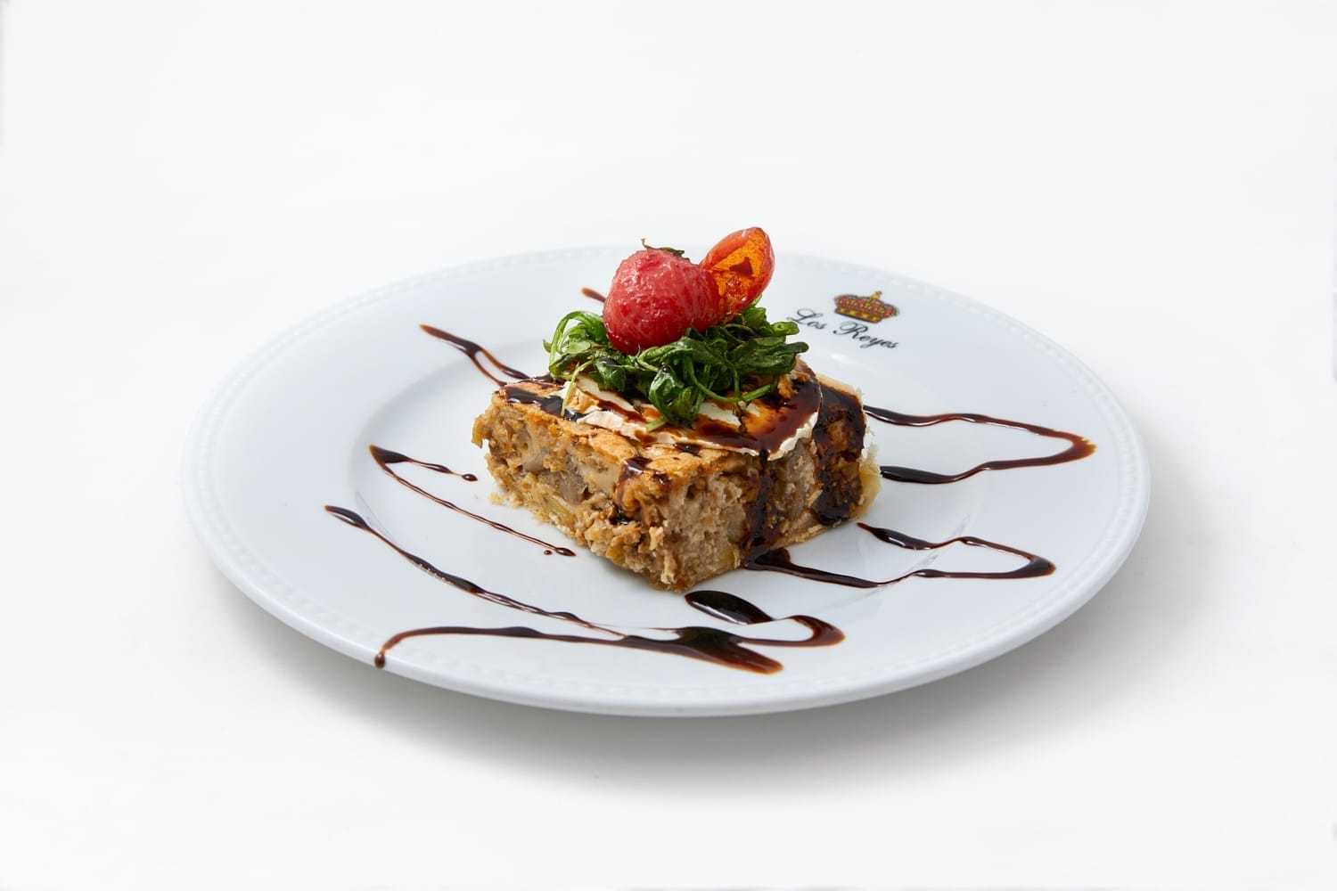 Pastel de berenjena con queso de cabra, rúcula frita y tomatito cherry